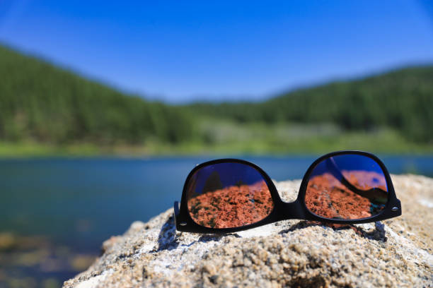 Polarized sunglasses on top of a rock by a lake